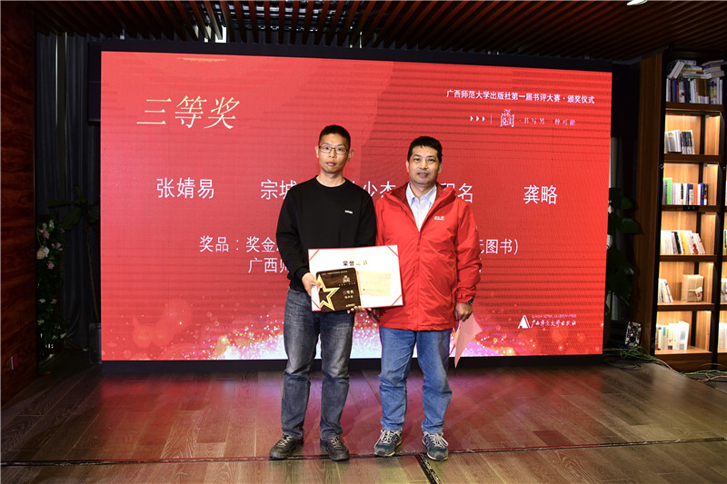 廣西師范大學(xué)出版社集團首席編輯沈偉東（右）為三等獎獲得者孫少杰頒發(fā)獎牌及榮譽(yù)證書(shū)（李顯楊攝）.jpg